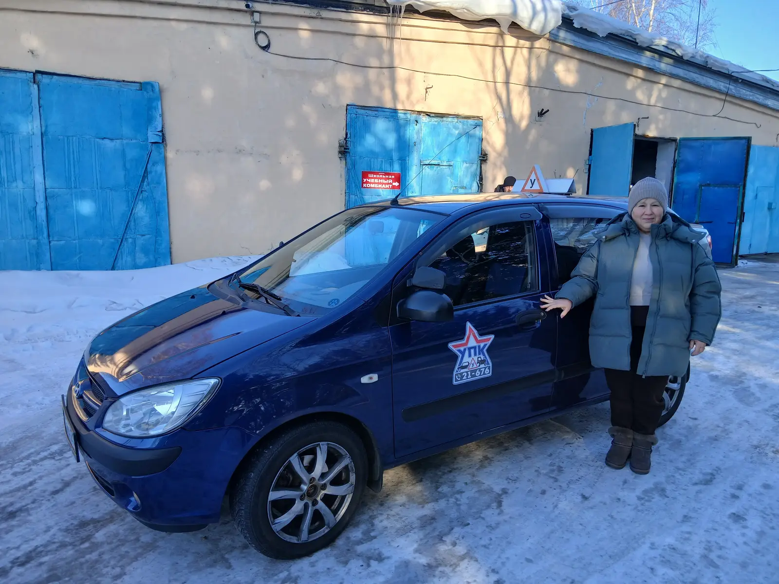 Синий учебный автомобиль со знаком «У» у гаражей учебного комбината, зима